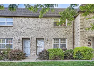 Charming townhome featuring a brick facade, well-manicured lawn, and lush landscaping at 5511 S Lowell Blvd, Littleton, CO 80123