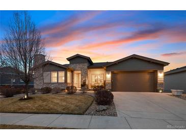 Charming single-story home with a two-car garage, stone accents, and a well-maintained lawn at dusk at 12371 Red Fox Way, Broomfield, CO 80021