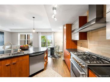 Modern kitchen featuring stainless steel appliances, dark countertops, and light wood cabinets with an adjacent breakfast nook at 2240 N Clay St # 309, Denver, CO 80211