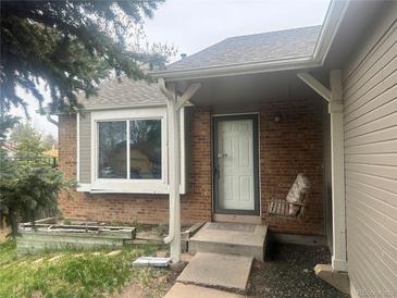 Charming brick home featuring a cozy front porch swing and large window at 19351 E Purdue Cir, Aurora, CO 80013