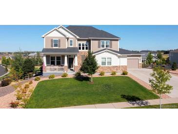 Inviting two-story home featuring manicured lawn, charming porch and a neutral color palette at 23230 E Rockinghorse Pkwy, Aurora, CO 80016