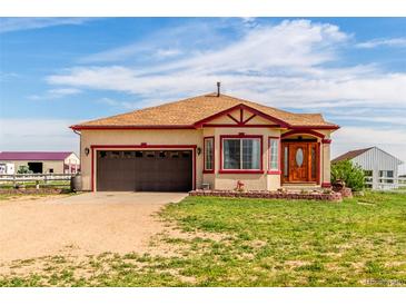 Tan home with brown garage door and red trim nestled on a sprawling green lawn with blue skies above at 46303 E 106Th Ave, Bennett, CO 80102