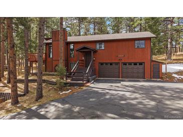 Charming home featuring an attached two-car garage and rustic exterior in a wooded area at 28630 Pine Dr, Evergreen, CO 80439