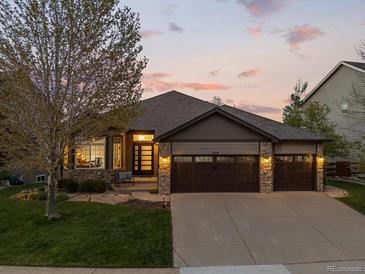 Charming ranch-style home showcasing stone accents, a spacious driveway, and a well-manicured lawn at sunset at 828 Rabbit Run Dr, Golden, CO 80401