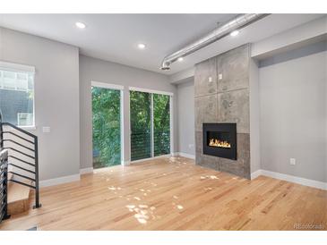 Bright living room features a modern fireplace, hardwood floors, and large windows showcasing the green outdoors at 2831 W 25Th Ave # 3, Denver, CO 80211