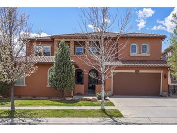 Two-story home featuring a red tiled roof, arched entry, two-car garage and a well-maintained lawn at 15314 W Baker Ave, Lakewood, CO 80228
