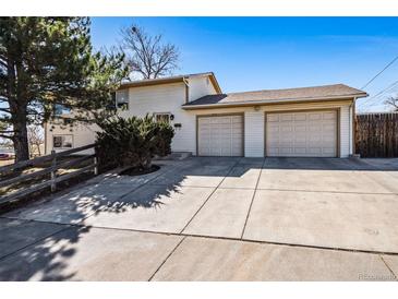 Charming home showcasing a spacious driveway and attached two-car garage, with a well-maintained yard and mature tree at 7815 Conifer Rd, Denver, CO 80221