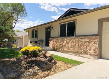 Charming single-story home featuring a stone accent wall, well-manicured lawn, and inviting outdoor seating at 6147 Dunraven, Golden, CO 80403