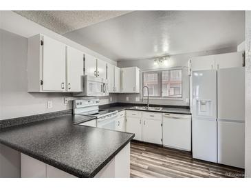 Bright kitchen with white cabinets, dark countertops, and modern appliances at 2740 W 86Th Ave # 186, Westminster, CO 80031