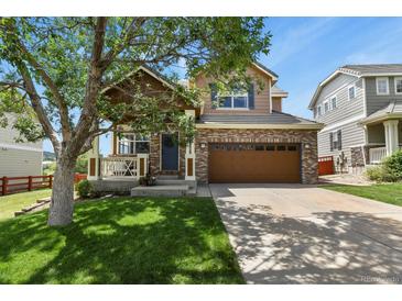 Charming two-story home showcasing a well-maintained front yard, inviting porch, and a brick two-car garage at 3912 Miners Candle Pl, Castle Rock, CO 80109