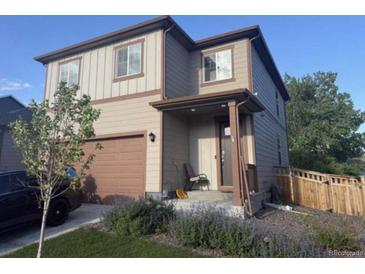 Charming two-story home boasts neutral siding, a two-car garage, and a cozy front porch perfect for relaxing at 502 Ledge St, Brighton, CO 80603