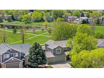 Beautiful aerial view of a home backing to a lush green park, walking path and pond at 3418 Elk Ct, Broomfield, CO 80020