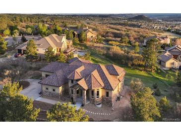 Expansive home showcasing a detailed tile roof, complemented by lush trees and a picturesque view at 4605 Tierra Alta Dr, Castle Rock, CO 80104