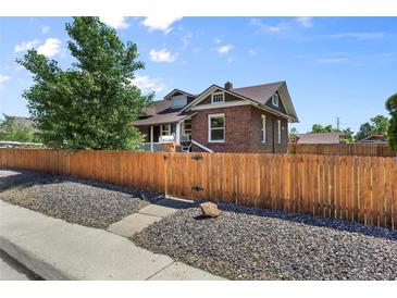 Charming brick home with a wooden fence and a well-manicured front yard at 5008 Sherman St, Denver, CO 80216