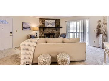 Inviting living room with a stone fireplace, neutral colors, and comfortable seating arrangements at 18064 E Ohio Ave # 103, Aurora, CO 80017