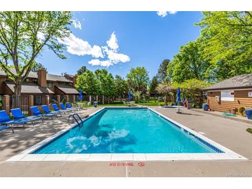 Community pool with lounge chairs and lush landscaping and blue skies with some cloud coverage at 9400 E Iliff Ave # 88, Denver, CO 80231