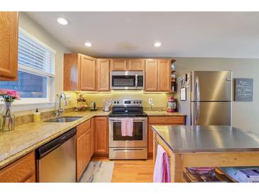 A modern kitchen with stainless steel appliances, light wood cabinets, and granite countertops at 5809 S Pearl St, Centennial, CO 80121