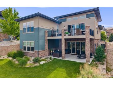 Spacious backyard featuring a patio, balcony, well-kept lawn, and inviting outdoor seating areas at 817 Backcountry Ln, Highlands Ranch, CO 80126