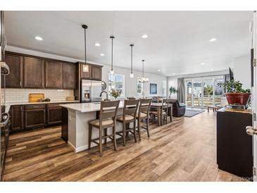 Open-concept kitchen features wood floors, stainless appliances, large island with bar seating, and easy access to a living area at 5670 Pinto Valley St, Parker, CO 80134