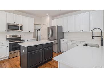 Bright kitchen boasts stainless appliances, a center island, and ample white cabinetry at 11973 Song Bird Hills St, Parker, CO 80138