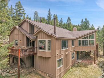 Multi-story home with wood facade, deck, and large windows surrounded by trees and sky at 3726 Spring Valley Trl, Evergreen, CO 80439