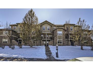 Attractive 3-story building with snow-covered landscaping at 5800 Tower Rd # 103, Denver, CO 80249