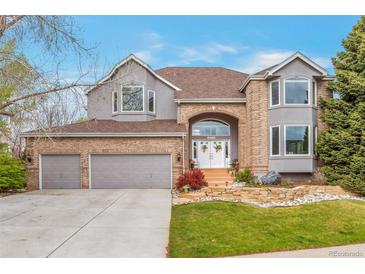 Beautiful two-story home with brick and stucco, arched entryway, three-car garage, and professionally landscaped front yard at 10773 Cougar Rdg, Lone Tree, CO 80124