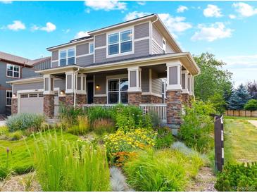 Charming two-story home featuring a welcoming front porch and beautifully landscaped front yard with vibrant flowers at 1902 Pioneer Cir, Lafayette, CO 80026