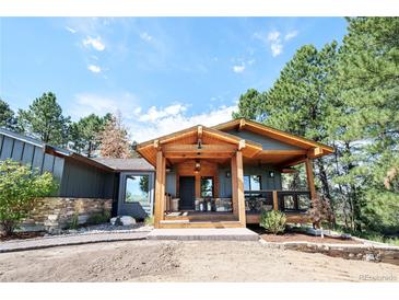 Inviting home features a cozy wood porch and stone accents, creating a warm and welcoming entrance at 2231 Meadow Green Cir, Franktown, CO 80116