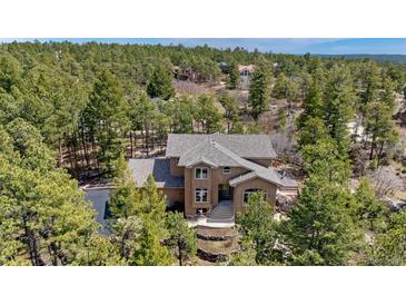 Stunning two-story home surrounded by lush greenery featuring an arched entryway and a neutral-toned facade at 19595 E Top O The Moor Dr, Monument, CO 80132