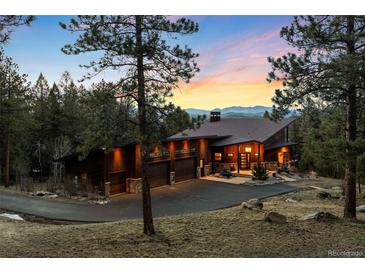 Stunning modern home featuring a three-car garage and a lush, wooded landscape with mountain views at 5976 Stone Creek Dr, Evergreen, CO 80439