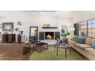 Cozy living room with a brick fireplace, wood floors, modern decor, and large window at 7250 Eastmoor Dr # 203, Denver, CO 80237
