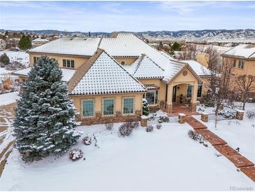 Luxury home with snow covered landscaping, mountain views, and stone accents at 774 Chamberlain Way, Highlands Ranch, CO 80126