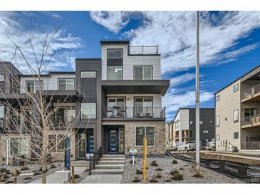 Modern two-story townhome with dark and light exterior finishes, balcony, and walkway at 1714 Peak Loop, Broomfield, CO 80023