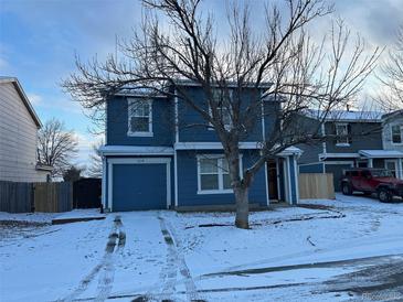 Two-story home featuring blue siding, white trim, an attached garage, and a snow-covered front yard with a bare tree at 5218 E 100Th Pl, Thornton, CO 80229