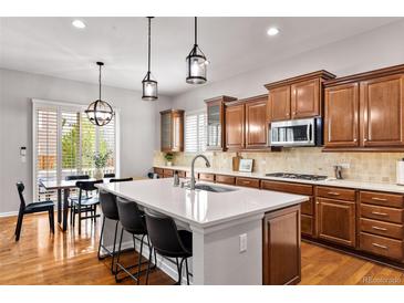 Beautiful kitchen features a large island with seating, stainless steel appliances and modern pendant lighting at 14134 Glenayre Cir, Parker, CO 80134
