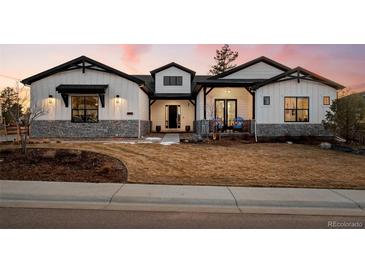 Charming two-story home featuring white siding, stone accents, a well-manicured lawn, and a welcoming front porch at 6001 Powell Rds, Parker, CO 80134