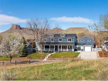 Charming two-story blue home with a covered front porch and lush lawn against a mountain backdrop at 2221 Illinois St, Golden, CO 80401