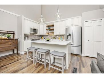 Bright kitchen with quartz countertops, stainless steel appliances, kitchen island and pendant lighting at 6513 Pinewood Dr, Parker, CO 80134