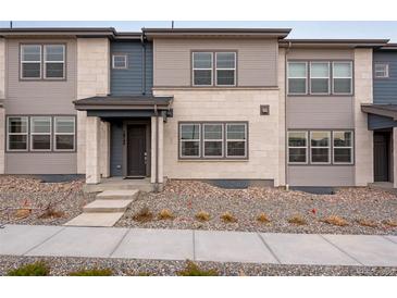 Charming townhome featuring a modern facade and inviting entrance with a covered porch and manicured landscape at 16744 W 93Rd Pl, Arvada, CO 80007