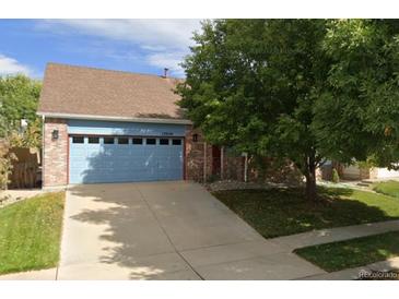 Charming single-Gathering home with a well-manicured lawn, brick facade, and a blue garage door at 13959 E 106Th Ave, Commerce City, CO 80022