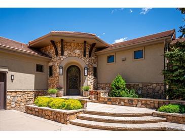 Stunning stone front entrance featuring a decorative door, stone archway, and meticulously landscaped surroundings at 6194 Falcon Ridge Way, Morrison, CO 80465