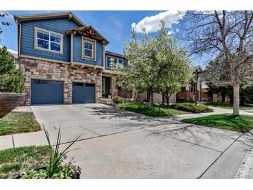 Charming two-story home with a stone facade, blue siding, a two-car garage, and a well-manicured front yard at 25245 E Park Crescent Dr, Aurora, CO 80016