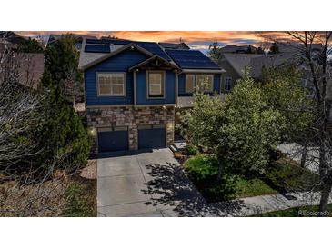 Beautiful two-story home featuring a stone and blue-paneled facade, two-car garage, solar panels and landscaped front yard at 25245 E Park Crescent Dr, Aurora, CO 80016