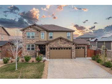 Beautiful two-story home featuring stone accents, a three-car garage, and a well-manicured lawn at 25064 E Archer Pl, Aurora, CO 80018