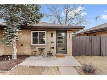 Charming single-story home features a brick facade, modern front door, and cozy outdoor seating area at 2810 N Harrison St, Denver, CO 80205