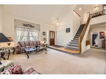 Inviting living room featuring a soaring ceiling, plush carpet, and a staircase leading to the upper level at 9001 W Chatfield Dr, Littleton, CO 80128