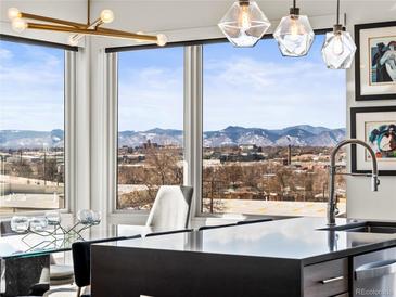 Gourmet kitchen with a modern island, stainless steel appliances, and mountain views from large windows at 1898 S Bannock St # 404, Denver, CO 80223