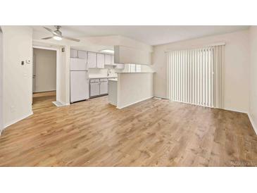 Bright living room featuring wood floors, sliding glass door, and an opening to the kitchen with white cabinets at 17053 E Tennessee Dr # 101, Aurora, CO 80017