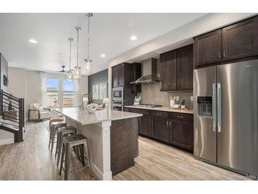 Modern kitchen featuring stainless steel appliances, pendant lighting, and a spacious island with bar seating at 9072 E 47Th Ave, Denver, CO 80238